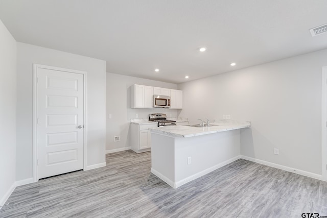 kitchen featuring stainless steel appliances, white cabinetry, sink, light hardwood / wood-style floors, and kitchen peninsula