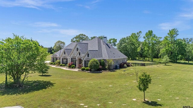 21882 Syrah Dr, Tyler, TX 75703 - view of side of home with stone siding, a chimney, and a lawn