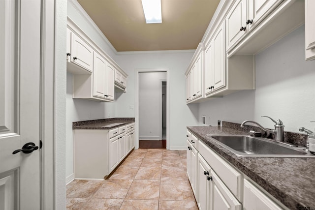 21882 Syrah Dr, Tyler, TX 75703 - kitchen with a sink, dark countertops, ornamental molding, white cabinets, and light tile patterned floors