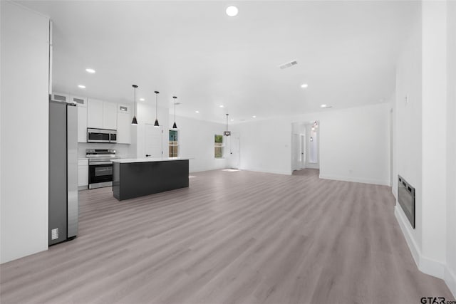 unfurnished living room with heating unit, a barn door, and light hardwood / wood-style floors