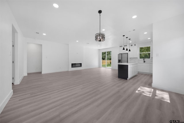 unfurnished living room with light hardwood / wood-style flooring, a chandelier, and sink