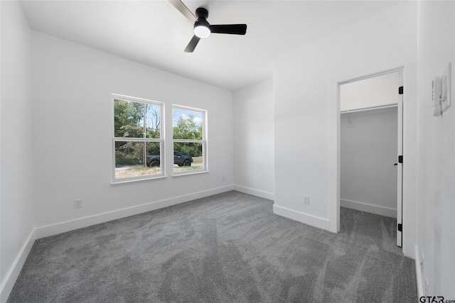 unfurnished bedroom featuring ceiling fan, carpet flooring, a closet, and a spacious closet