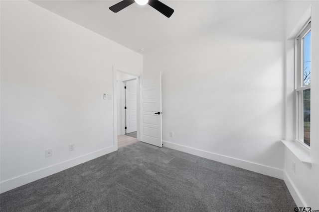 spare room with ceiling fan and dark colored carpet