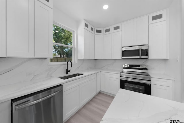 kitchen featuring light hardwood / wood-style flooring, sink, light stone countertops, white cabinetry, and appliances with stainless steel finishes