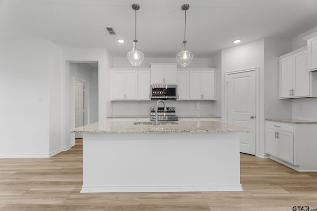 kitchen featuring a kitchen island with sink, sink, stainless steel appliances, and white cabinets