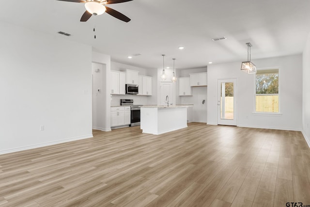 unfurnished living room featuring ceiling fan, sink, and light wood-type flooring