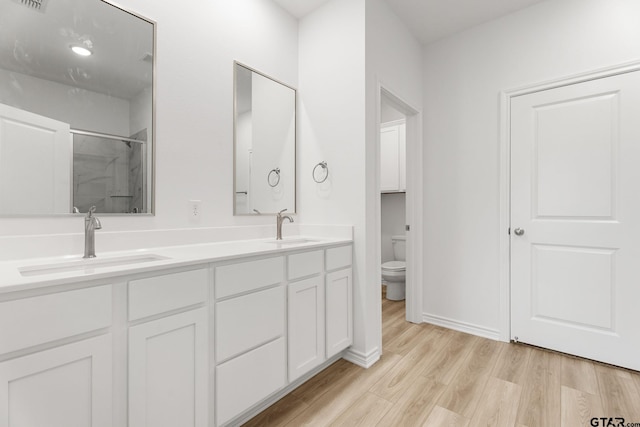 bathroom with vanity, hardwood / wood-style floors, a shower with door, and toilet