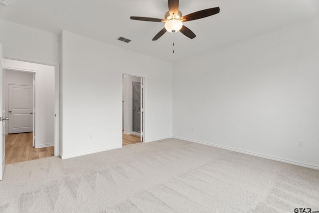 unfurnished bedroom with ceiling fan, a spacious closet, and light colored carpet