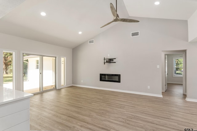 unfurnished living room featuring ceiling fan, high vaulted ceiling, light wood-type flooring, and heating unit