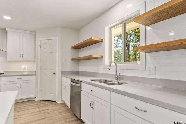 kitchen featuring sink, white cabinets, light hardwood / wood-style floors, stainless steel dishwasher, and backsplash