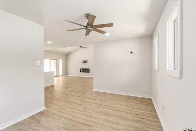 empty room with ceiling fan, light hardwood / wood-style flooring, heating unit, and lofted ceiling