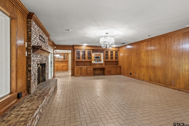 1108 Quitman, Pittsburg, TX 75686 - unfurnished living room featuring brick patterned floors, wooden walls, a fireplace, a chandelier, and ornamental molding
