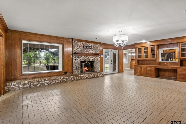 1108 Quitman, Pittsburg, TX 75686 - unfurnished living room with a chandelier, wooden walls, plenty of natural light, a fireplace, and ornamental molding