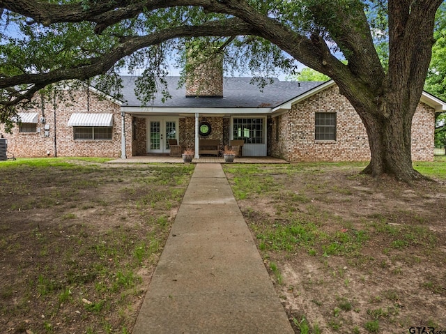 1108 Quitman, Pittsburg, TX 75686 - view of front of property with french doors, brick siding, a chimney, central AC, and a shingled roof