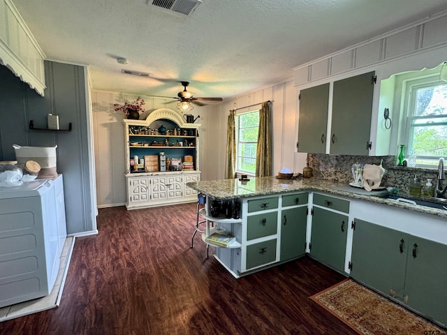 kitchen featuring a textured ceiling, sink, light stone counters, and dark hardwood / wood-style flooring