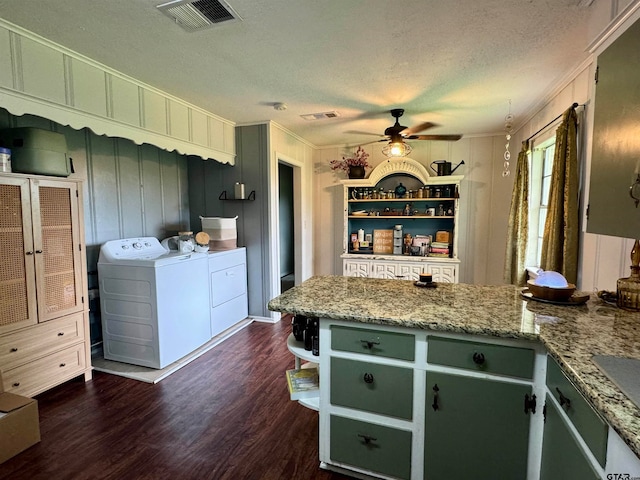 kitchen with light stone countertops, a textured ceiling, crown molding, dark wood-type flooring, and washing machine and dryer