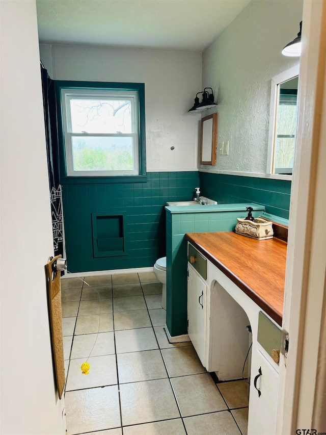 bathroom featuring vanity, tile patterned flooring, toilet, and tile walls