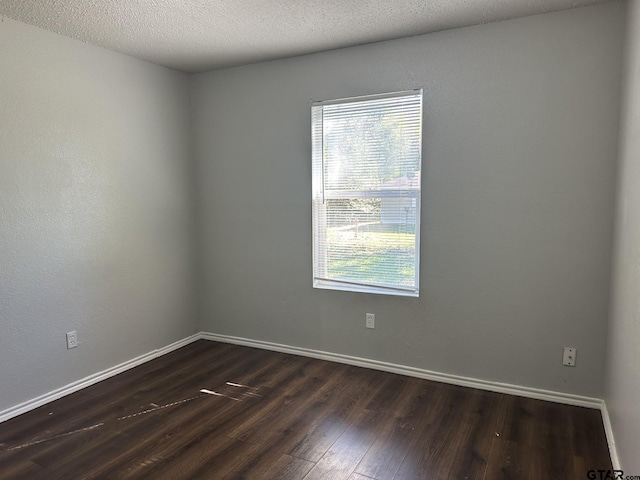 empty room featuring dark wood-type flooring and a textured ceiling