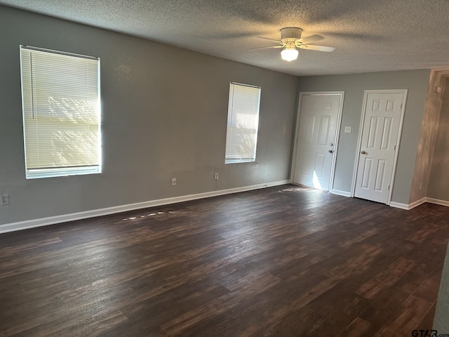 empty room with a textured ceiling, ceiling fan, and dark hardwood / wood-style floors