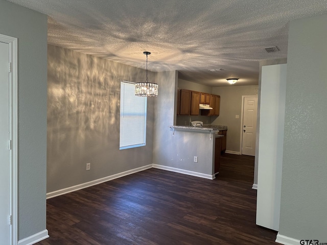 interior space featuring kitchen peninsula, a kitchen breakfast bar, hanging light fixtures, and dark wood-type flooring