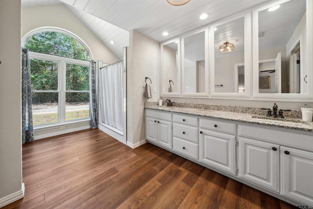 bathroom featuring hardwood / wood-style flooring, vaulted ceiling, a healthy amount of sunlight, and vanity