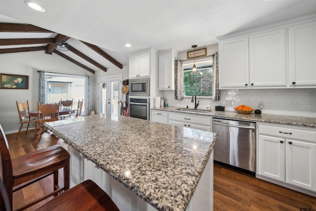 kitchen with appliances with stainless steel finishes, dark hardwood / wood-style floors, white cabinetry, sink, and a kitchen breakfast bar