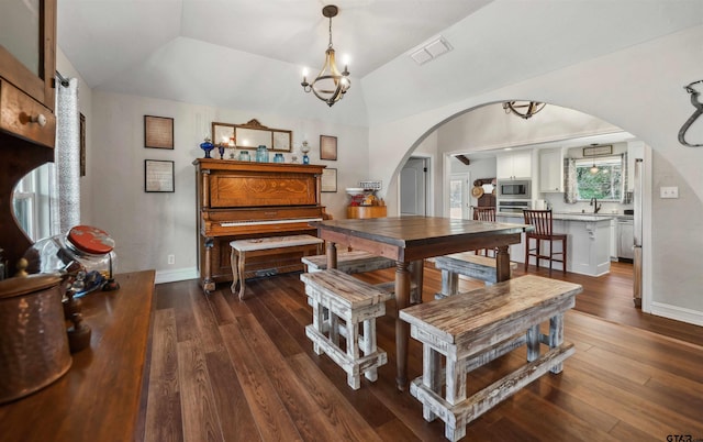 dining area with dark hardwood / wood-style flooring, a notable chandelier, and vaulted ceiling