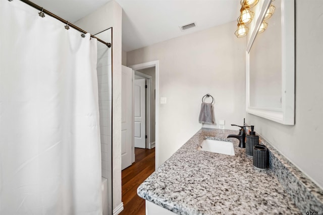 bathroom with hardwood / wood-style flooring, shower / tub combo with curtain, and vanity