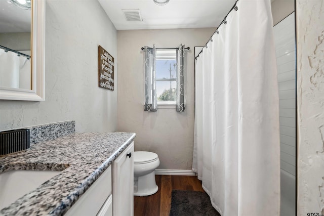 bathroom with hardwood / wood-style flooring, vanity, walk in shower, and toilet