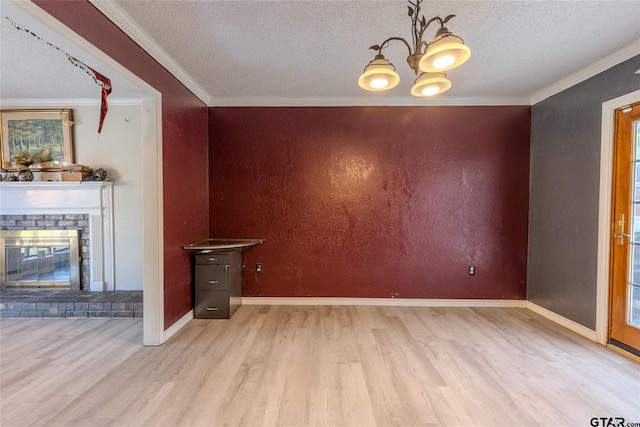 1304 Azalea Dr, Sulphur Springs, TX 75482 - unfurnished dining area featuring light wood-style floors, a chandelier, a textured ceiling, ornamental molding, and a fireplace