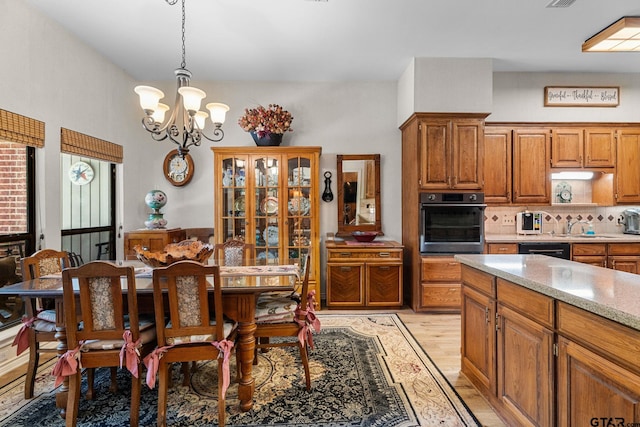 19132 Falls Creek Dr, Flint, TX 75762 - kitchen with light wood finished floors, wall oven, a notable chandelier, brown cabinetry, and hanging light fixtures