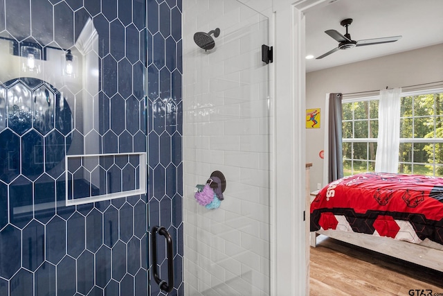 bathroom with hardwood / wood-style floors, ceiling fan, and a shower with shower door