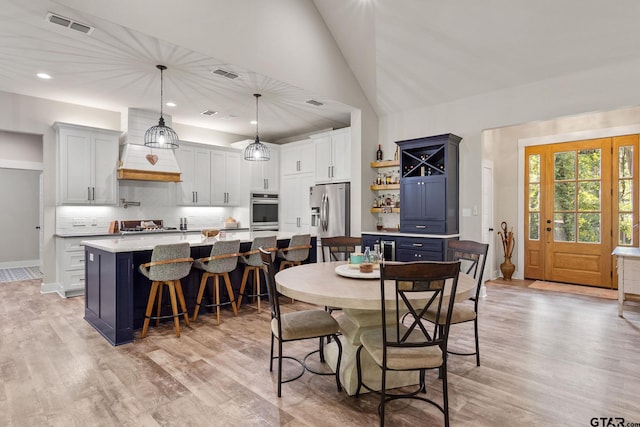 dining room featuring light hardwood / wood-style floors and high vaulted ceiling