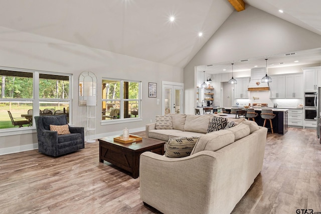 living room with high vaulted ceiling, light hardwood / wood-style flooring, and beamed ceiling