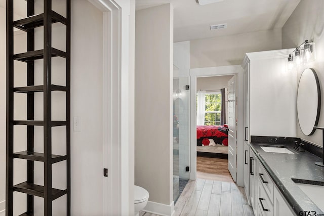 bathroom with an enclosed shower, wood-type flooring, toilet, and vanity