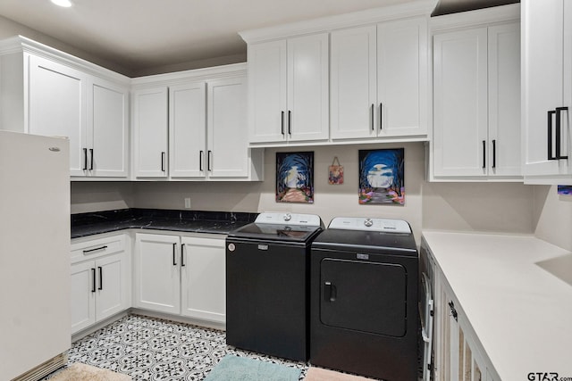 clothes washing area featuring light tile patterned floors, cabinets, and washing machine and clothes dryer