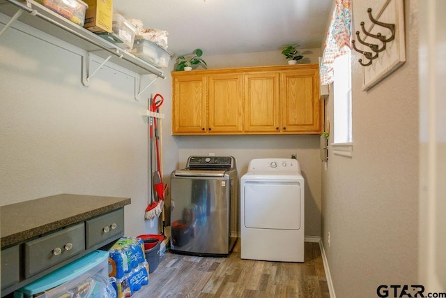 laundry area with light wood-type flooring, independent washer and dryer, cabinet space, and baseboards