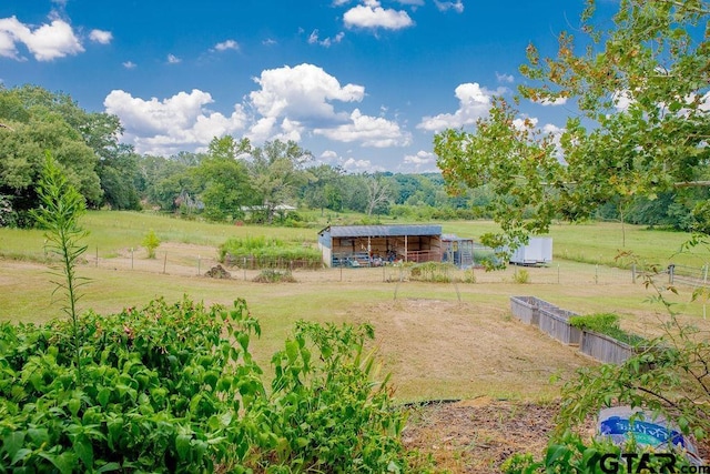 view of yard featuring a rural view, an outdoor structure, and fence