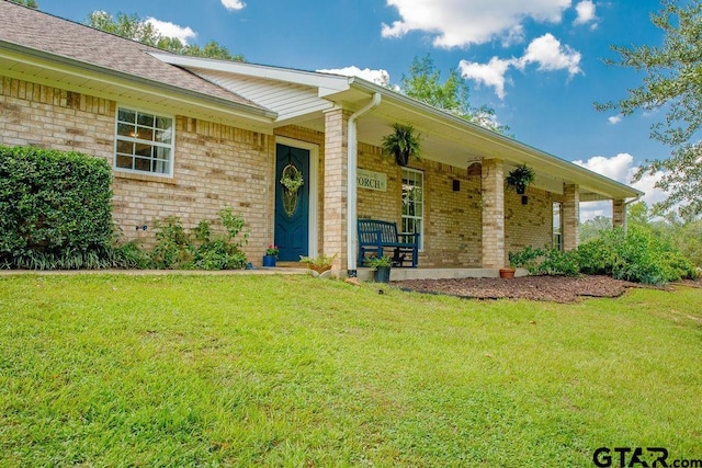 view of front of property featuring covered porch, a front yard, and brick siding