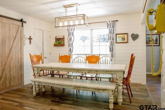 dining area with a barn door, wood walls, and wood finished floors