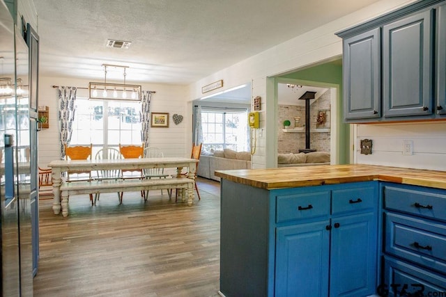 kitchen with blue cabinets, a wood stove, butcher block countertops, and visible vents