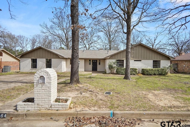 view of front of property featuring board and batten siding, a front yard, central air condition unit, and brick siding