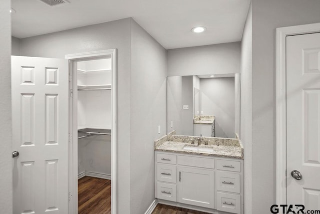 full bathroom with vanity, wood finished floors, baseboards, recessed lighting, and a walk in closet