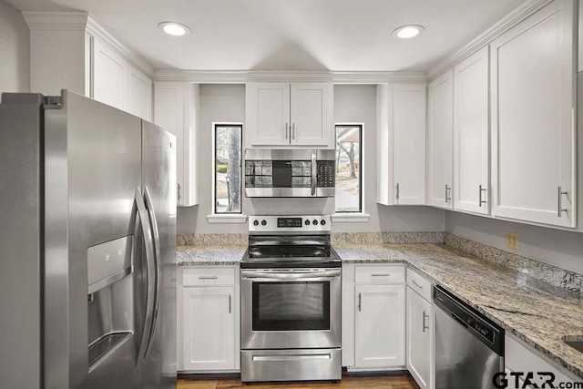 kitchen with light stone countertops, appliances with stainless steel finishes, and white cabinets