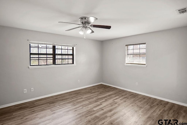 unfurnished room featuring a ceiling fan, wood finished floors, visible vents, and baseboards