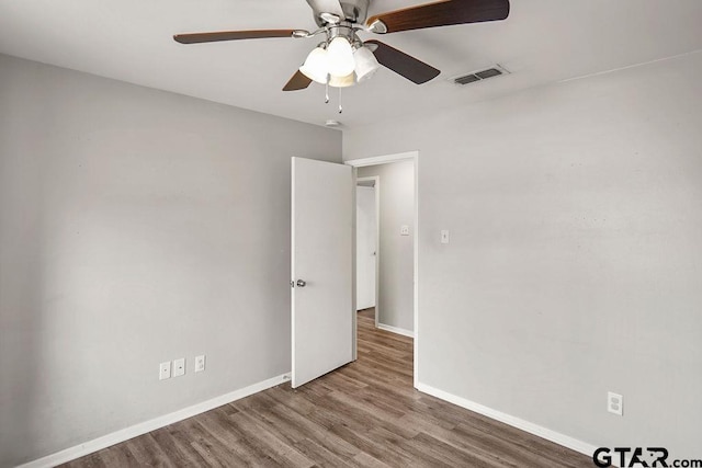 empty room with visible vents, a ceiling fan, baseboards, and wood finished floors