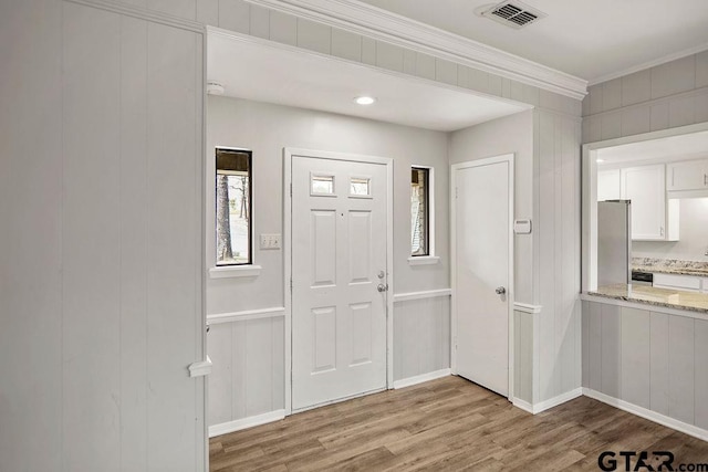 entrance foyer with visible vents, wood finished floors, and ornamental molding