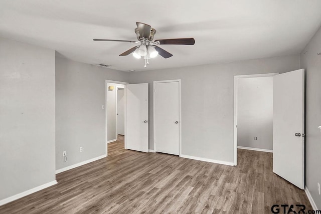 unfurnished bedroom featuring visible vents, wood finished floors, baseboards, and ceiling fan