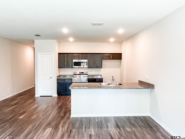 kitchen featuring appliances with stainless steel finishes, sink, dark hardwood / wood-style flooring, kitchen peninsula, and dark brown cabinets