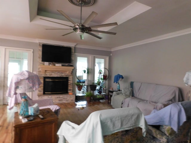 living room featuring ceiling fan, a wealth of natural light, wood finished floors, and a stone fireplace